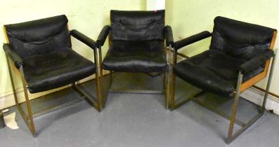 ATTRIBUTED TO WILLIAM PLUNKETT; a group of three mid century teak framed and leather elbow chairs.