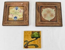 A group of three Art Nouveau tiles, two in oak frames, each 15 x 15cm.