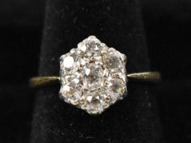 An 18ct yellow gold diamond set flower head ring, with central diamond surrounded by six smaller