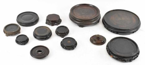 A group of nine Chinese carved hardwood stands and a bronze censer lid (10).