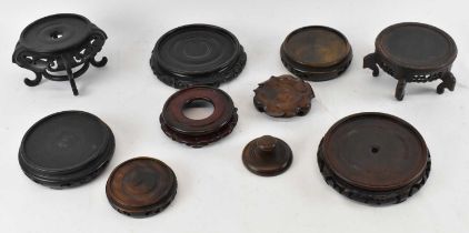 A group of nine Chinese carved hardwood stands and a hardwood ginger jar cover/lid (10).