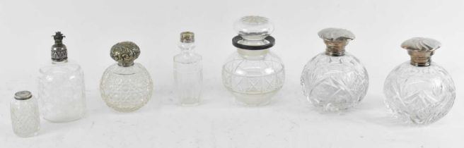 A group of seven white metal topped cut glass bottles, height of tallest 14.5cm.