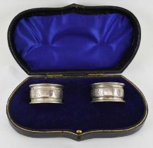 GEORGE UNITE; a cased pair of Victorian hallmarked silver napkin rings, inscribed 'I' and 'II',