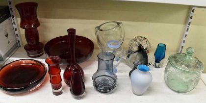 A group of art glass including green glass lidded jar, model of a fish, tall red glass vase, red