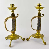 A pair of early 20th century brass candlesticks fashioned from sword handles, height 32cm.