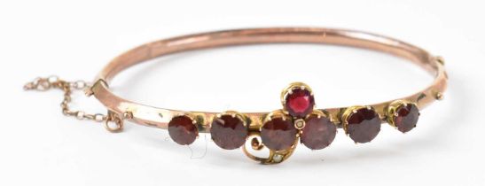 A 9ct yellow gold Edwardian bangle set with seven garnets,diameter 6.5cm, approx 5.7g.