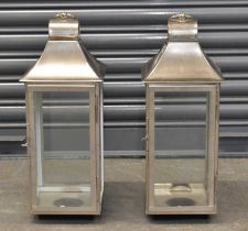 A pair of modern stainless steel lanterns, with swing loop handles to the top, height 53cm.