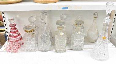 A group of eleven cut glass and crystal decanters, including a cranberry cut glass decanter with