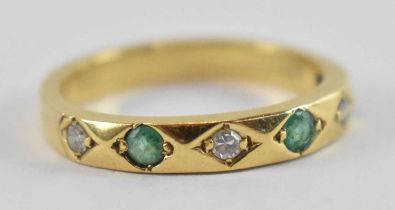 A yellow metal diamond and emerald ring, set with three small diamonds and three small emeralds,