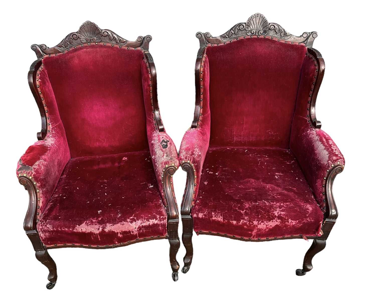 A pair of early 20th century carved mahogany framed and red upholstered armchairs (in need of