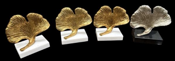 PLANTATION; a set of three modern contemporary gilt decorated leaf sculptures on white marble bases,