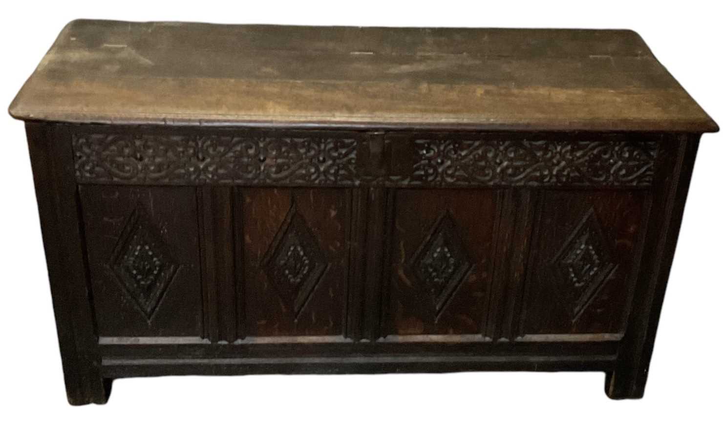 An 18th century carved oak coffer, with hinged lid and candle holder, width 142cm.