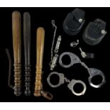 A group of three police truncheons, two pairs of handcuffs and two policemen's whistles, one