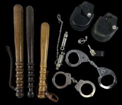 A group of three police truncheons, two pairs of handcuffs and two policemen's whistles, one