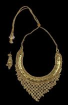 A yellow metal Pakistani wedding gift necklace, with gold drop tassels, and matching earring,