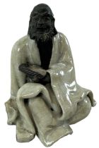 A Chinese figure of a beggar, draped in celadon glaze, height 8.5cm.