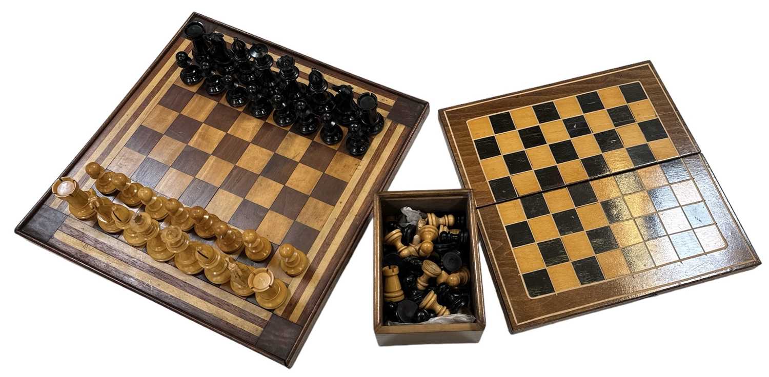 A cased Staunton chess set, another cased chess set, a games box and a chessboard, 39 x 39cm.