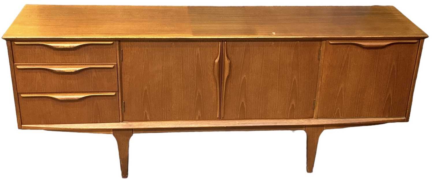 A teak mid century sideboard with three drawers, pair of cupboard doors and fall front cupboard