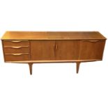 A teak mid century sideboard with three drawers, pair of cupboard doors and fall front cupboard