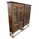 A pair of 1920s carved oak display cabinets on barley twist supports, height 190cm, width 96cm.