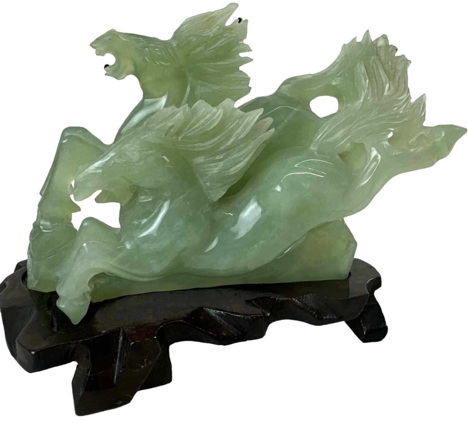 A modern Chinese green carved hardstone of two prancing horses, on carved hardwood base, height