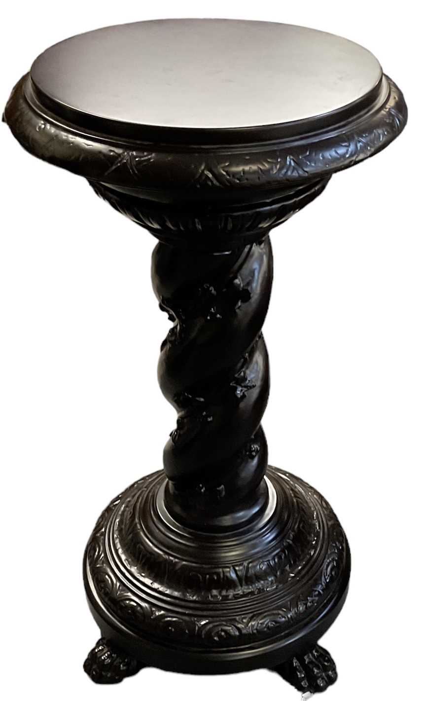 An impressive large ebonised stand with circular top and wrythen column terminating in four claw