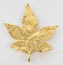 A yellow metal maple leaf pendant, height 4cm, width 3.5cm, approx 1.7g.