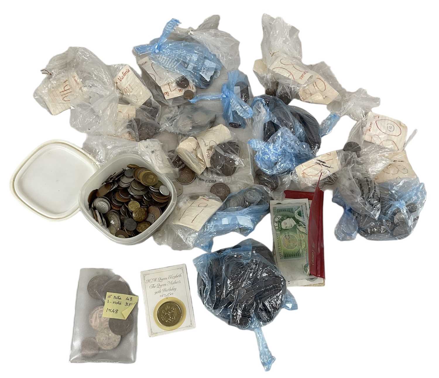 A quantity of all world coins and banknotes, including pound notes, pennies, sixpences, a silver