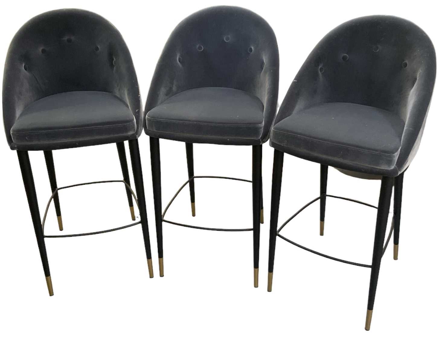 A set of three modern contemporary button back upholstered bar stools, on black metal supports,