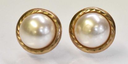 A pair of yellow metal and pearl set earrings, combined approx 0.9g.