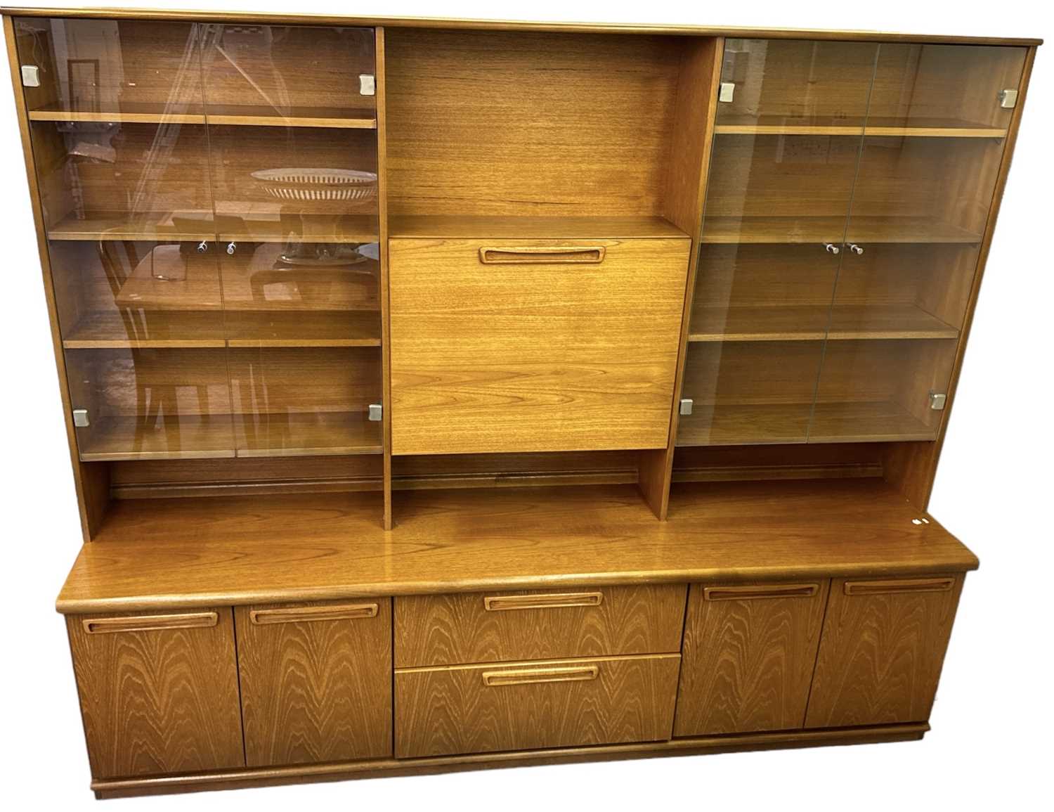 MEREDEW; a mid century teak wall unit, the pair of glazed cupboards flanking a central pull-down