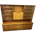 MEREDEW; a mid century teak wall unit, the pair of glazed cupboards flanking a central pull-down