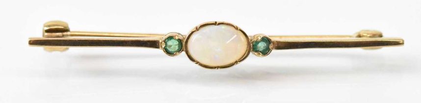 A 9ct yellow gold opal and emerald set bar brooch, the central opal flanked by two small emeralds,