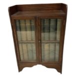 A 1920s oak display cabinet with pair of glazed doors, width 60cm, containing a full set of the