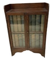 A 1920s oak display cabinet with pair of glazed doors, width 60cm, containing a full set of the