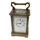 A brass cased carriage clock, the white enamel dial set with Roman numerals, height including handle