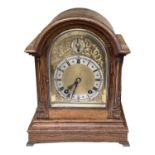 An early 20th century oak cased mantel clock with brass face and silvered dial set with Roman