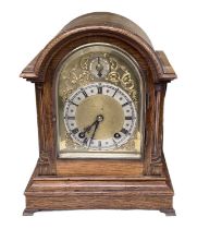 An early 20th century oak cased mantel clock with brass face and silvered dial set with Roman