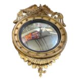 A 19th century convex gilt wood circular wall mirror, with eagle decoration to the top, height