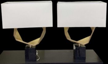 A pair of modern abstract sculptural gilt metal table lamps on black marble bases, with white