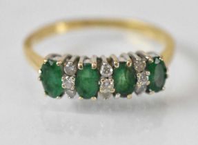An 18ct yellow gold emerald and diamond ring set with four emeralds and nine small diamonds, size O,
