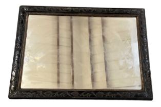 An early 20th century Chinese carved hardwood mirror, the frame decorated with carved foliage, 57