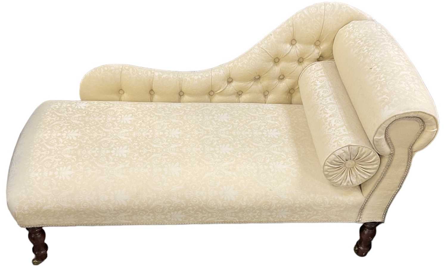 A reproduction mahogany cream upholstered chaise longue on turned supports, width approx 125cm.