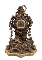 A modern ornate brass mantel clock decorated with cherubs and scrolling foliage, on marble base,