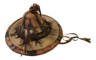 An African straw and feather decorated hat, diameter 42cm, head diameter 23cm.