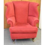 A good reproduction red upholstered wing armchair on turned supports with castors.