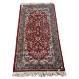 A red ground floral decorated rug with blue and cream border, 170 x 90cm.