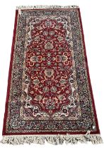 A red ground floral decorated rug with blue and cream border, 170 x 90cm.