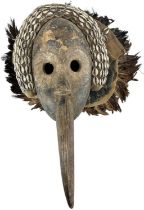 A Grebo Kru beak mask with shell decoration and feathers to the top, with cut eye holes, height