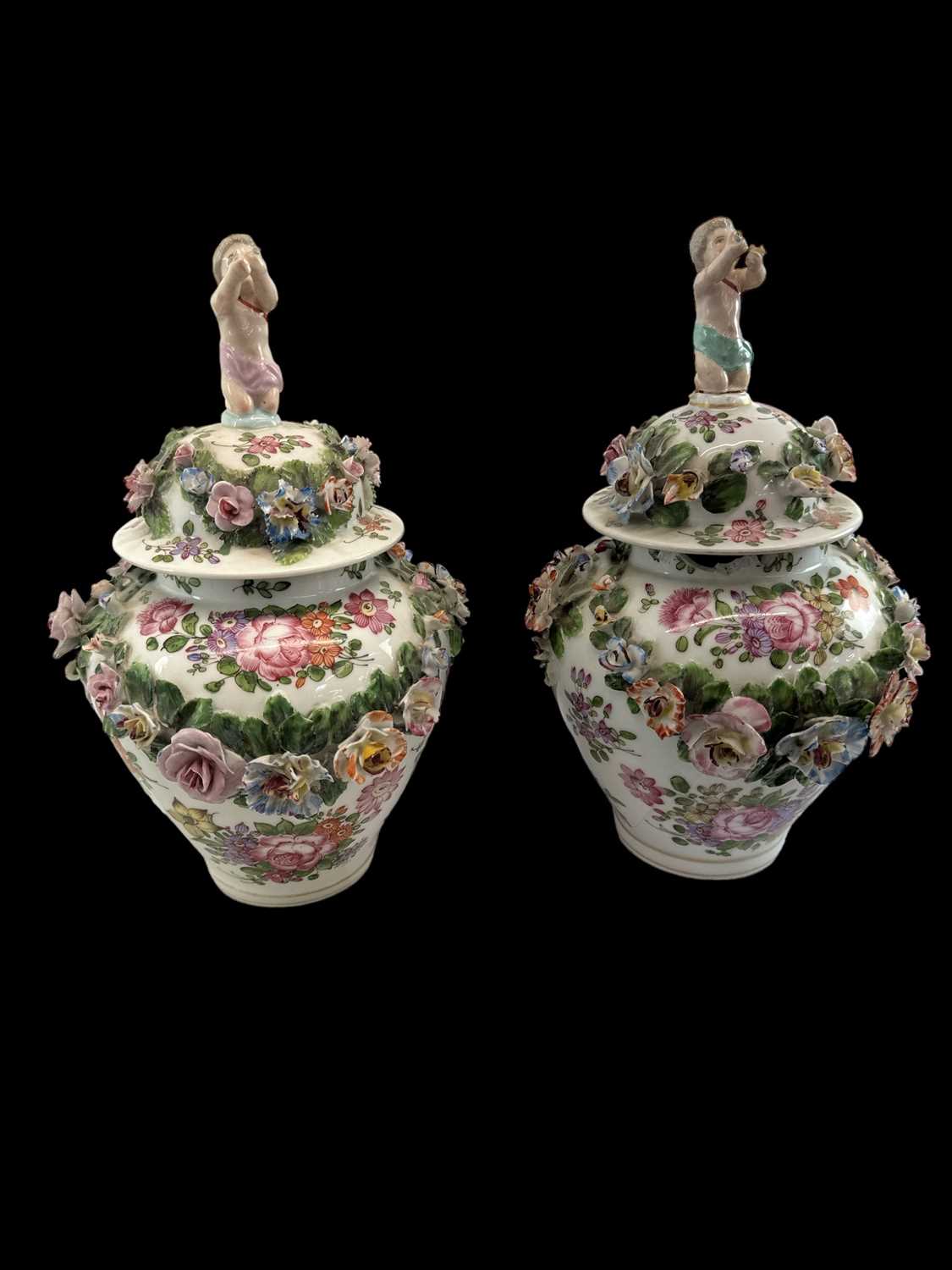 A pair of 19th century Continental floral encrusted and hand painted lidded urns with cherub
